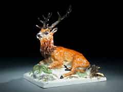 Detailabbildung: Porzellanfigur eines liegenden Hirschen auf Grassockel und rechteckiger Plinte