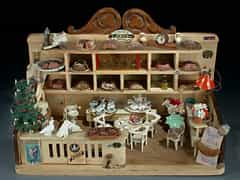 Puppenstube im Aufbau eines Caféhauses mit rückwertigem Wandregal, darin Kuchen und