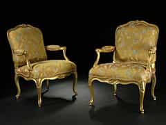 Paar Louis XV-Fauteuils Gestelle geschnitzt, gefasst und vollvergoldet mit geschweiften Beinen. Rücken und Sitz gepolstert, die vortretenden Armlehnen mit kurzen Polsterstücken in die geschweiften Zargen einlaufend. Innen Bekrönung in 