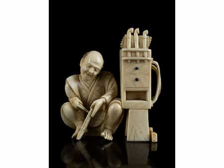 Okimono-Figur eines Pfeifenherstellers neben einem Werkzeugkasten